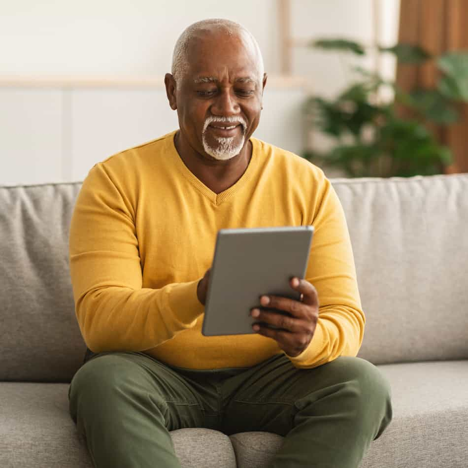 Older man on ipad investing with UPFCU.