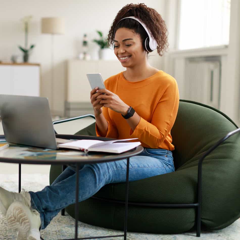 Young woman using laptop and iphone.