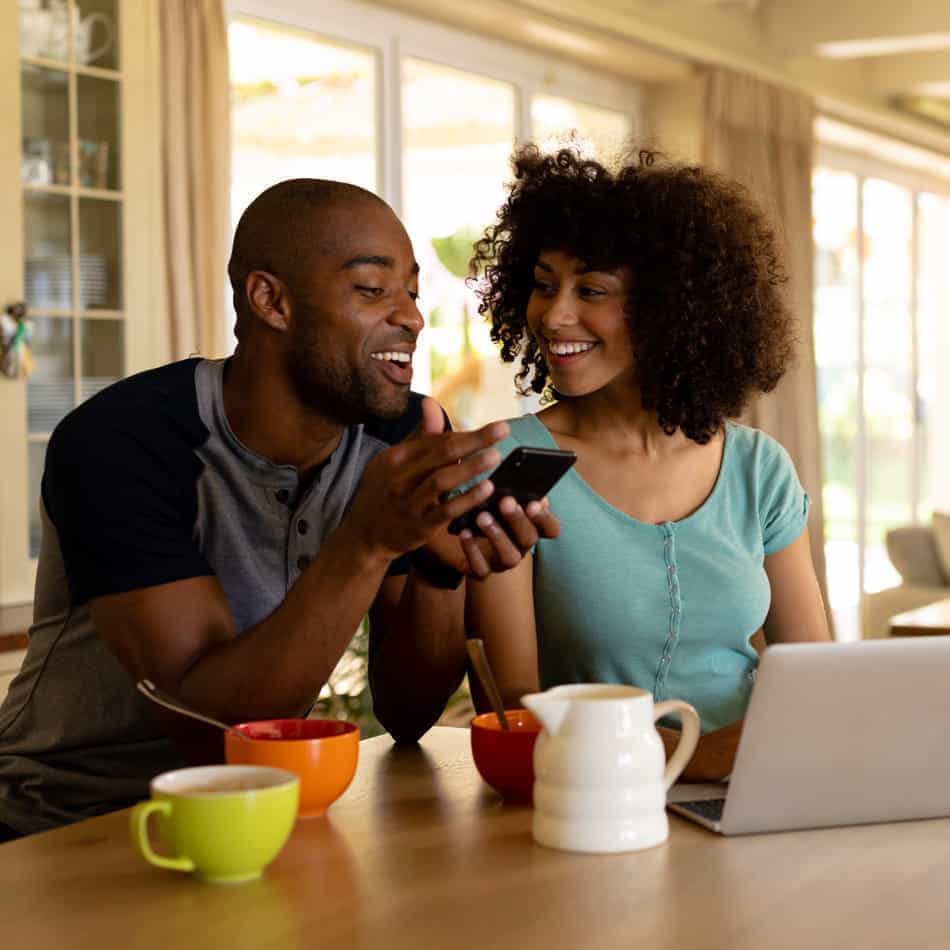 Couple in kitchen looking at iphone.
